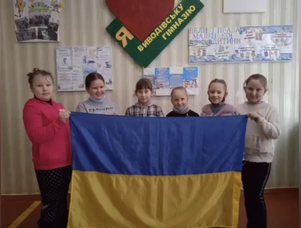 Students at Vyvodove Gymnasium holding the Ukrainian flag inside their classroom.